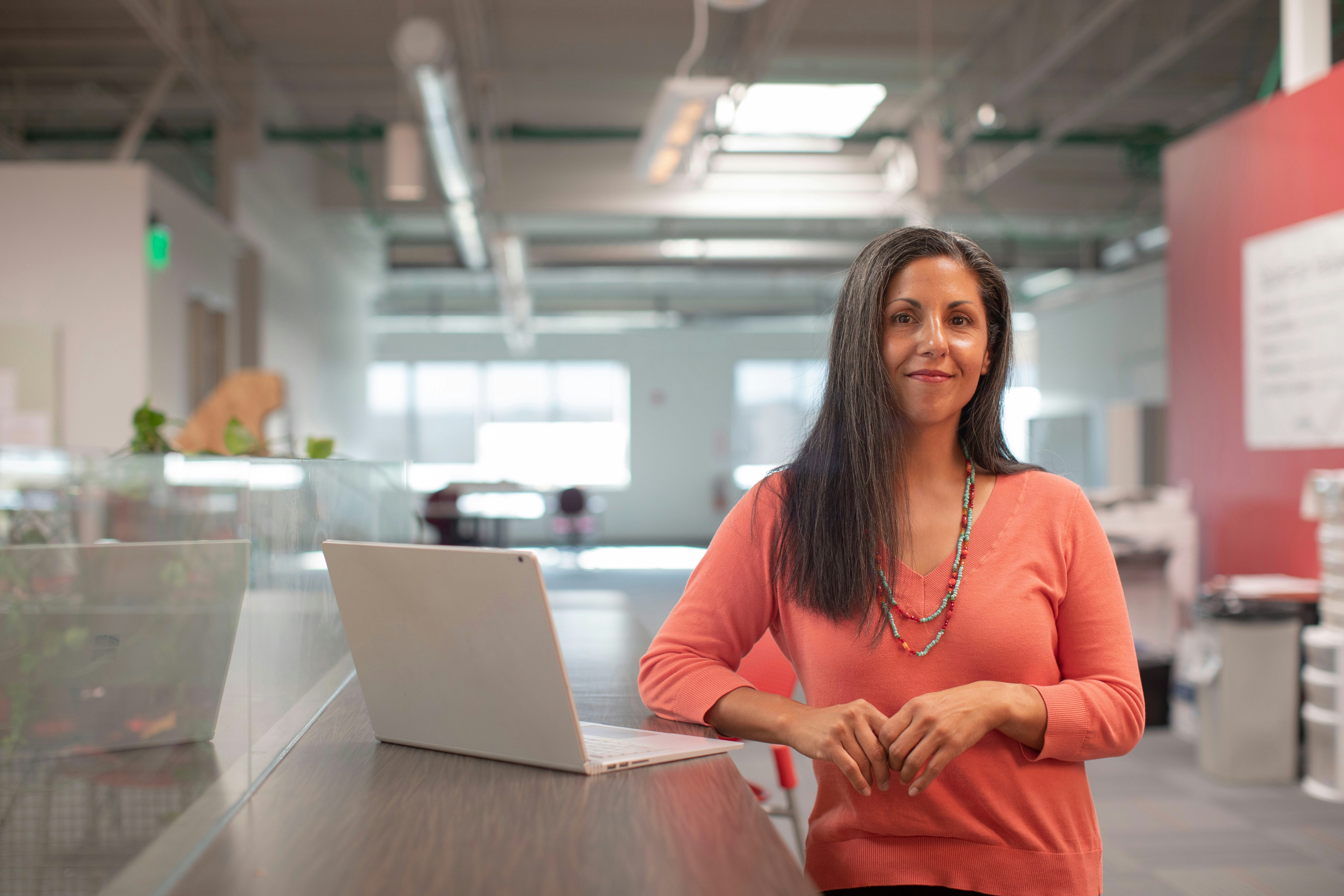 A woman is standing next to the laptop